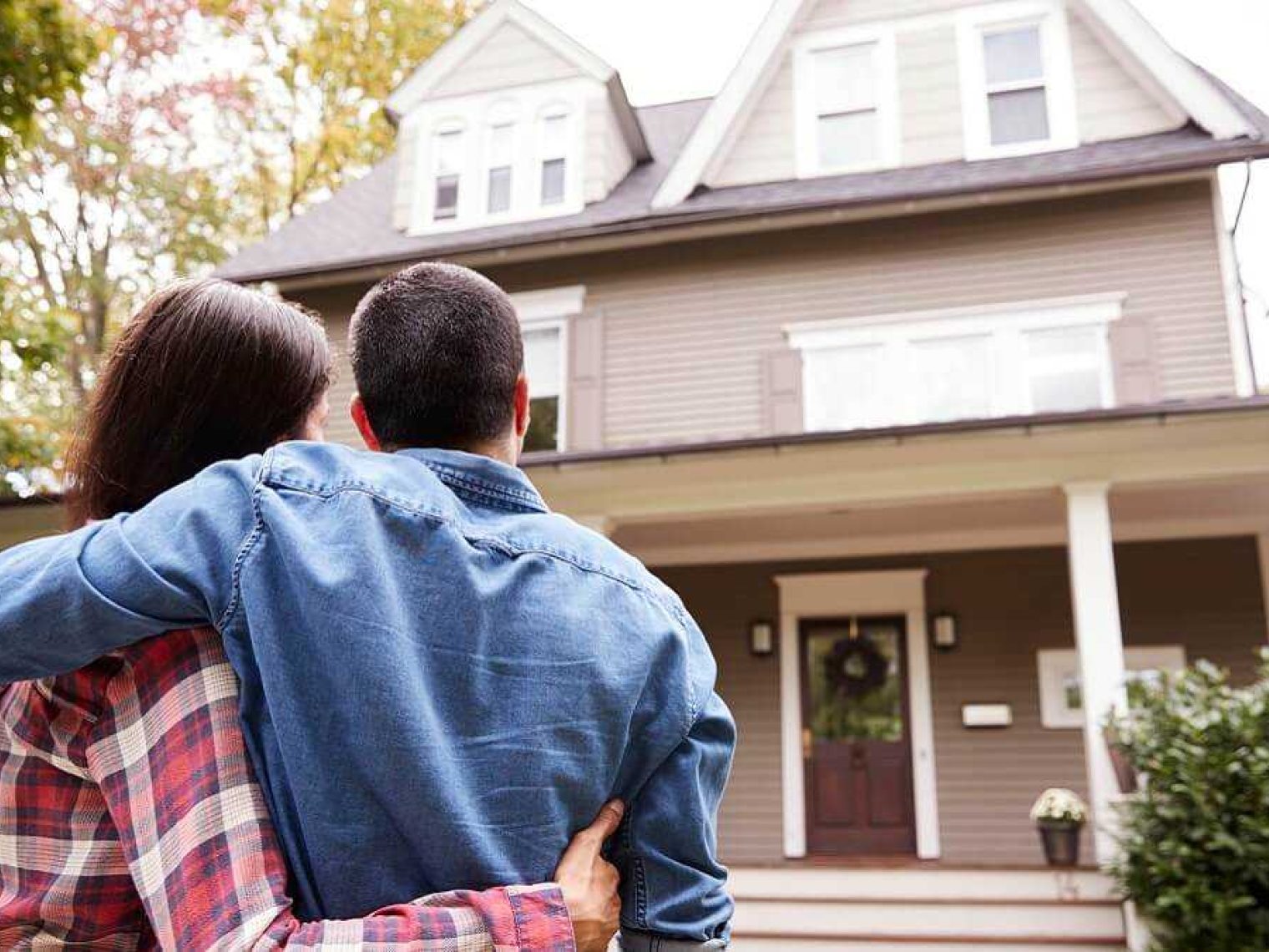 A couple standing admiring the outside of a house.