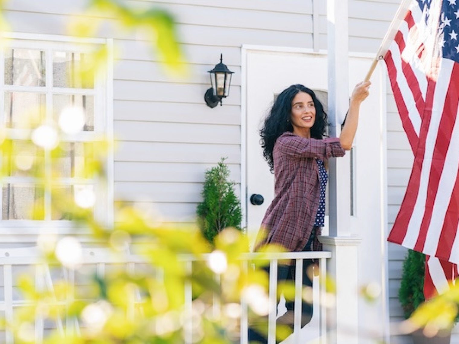 Woman hangs American flag outside of her home.