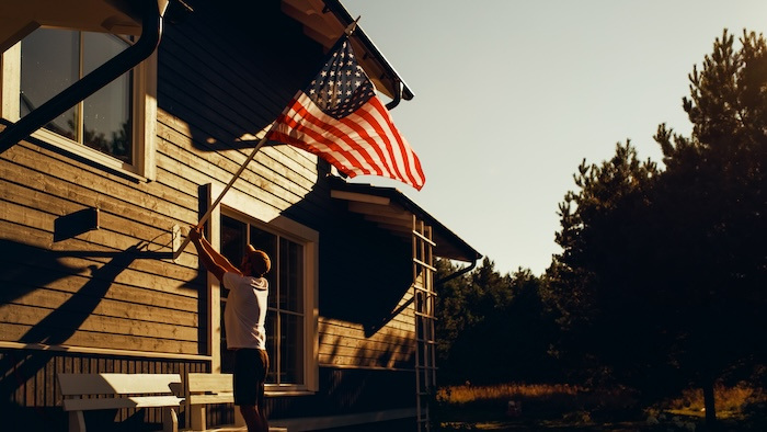 Man displaying the American flag on the outside of his home.